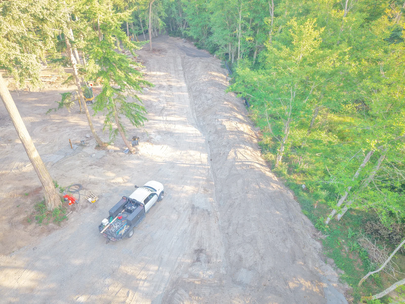 Aerial view of a cleared driveway and building site through the trees