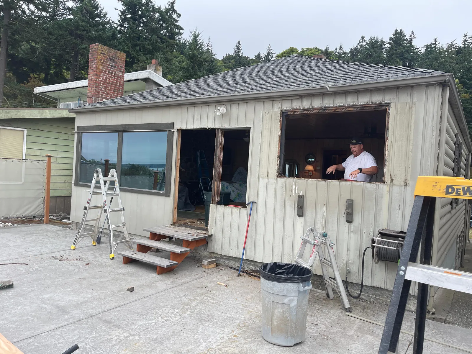 Carpenter standing in an old window opening during a cottage remodel