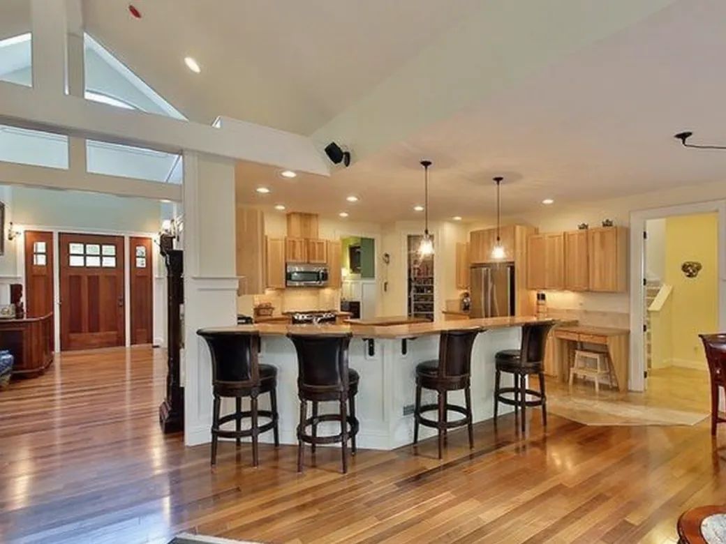 Open kitchen of a custom home with an island, bar stools and wood floors