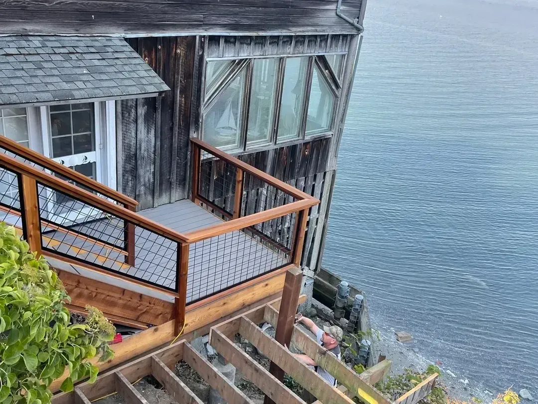 Deck and stairs being built down a waterfront bluff above the water