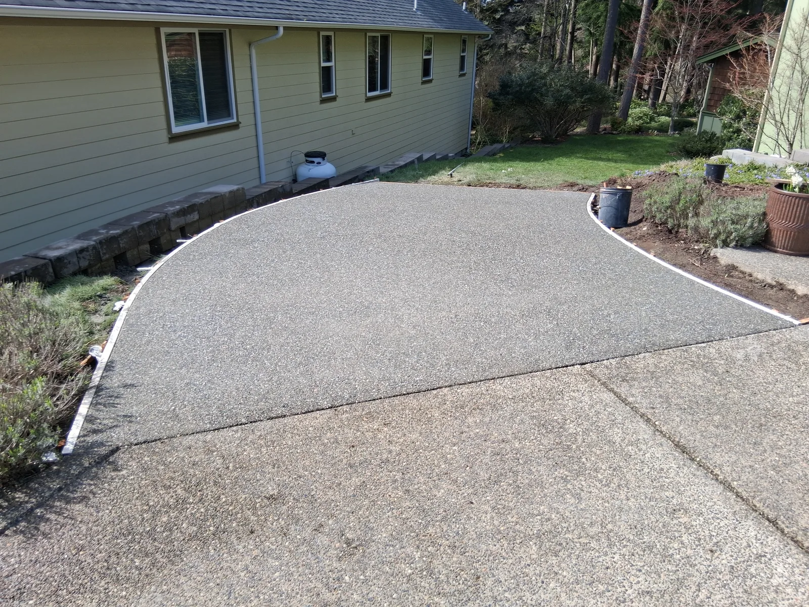 Exposed aggregate concrete driveway curving past a house