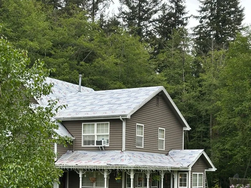 Two-story grey farmhouse with a covered front porch and a light grey roof