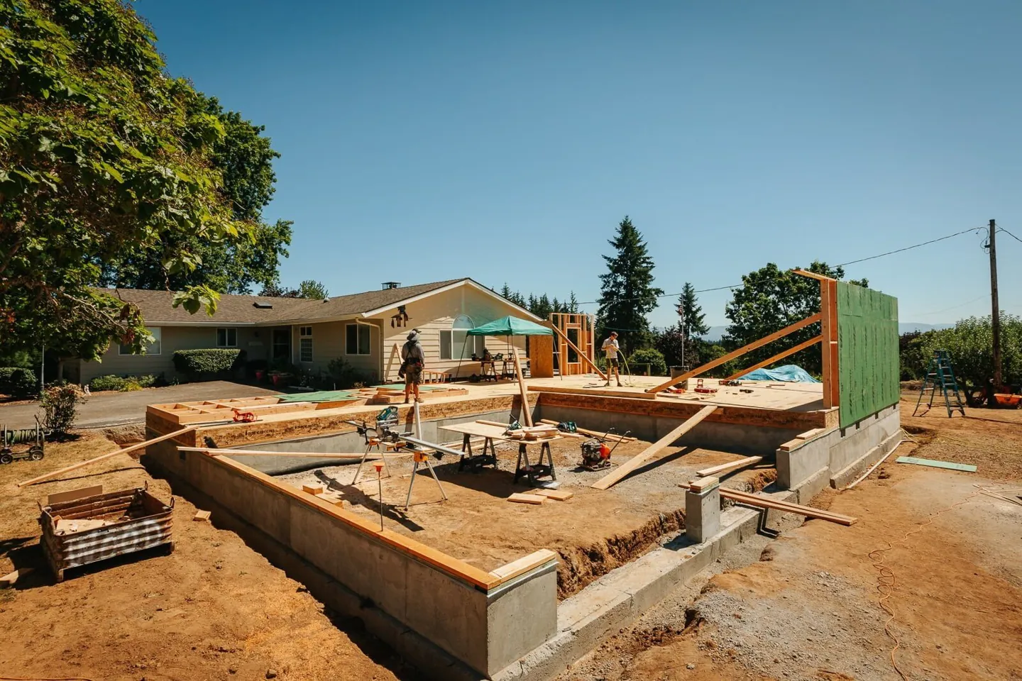 Foundation walls poured for a home addition beside a one-story house