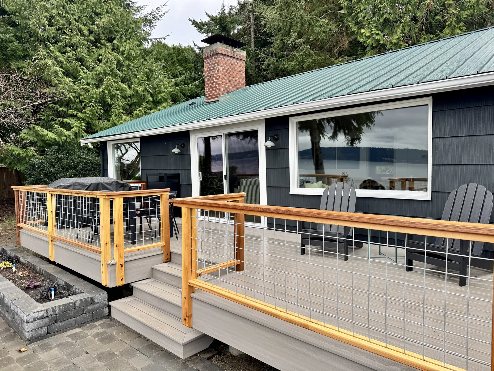 Dark blue island home with a green metal roof and a new cable-rail deck