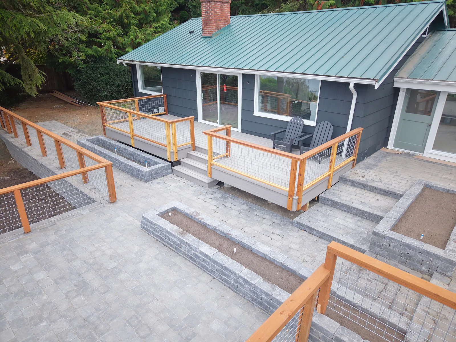 Paver patio and new deck at a dark blue island home with a green metal roof