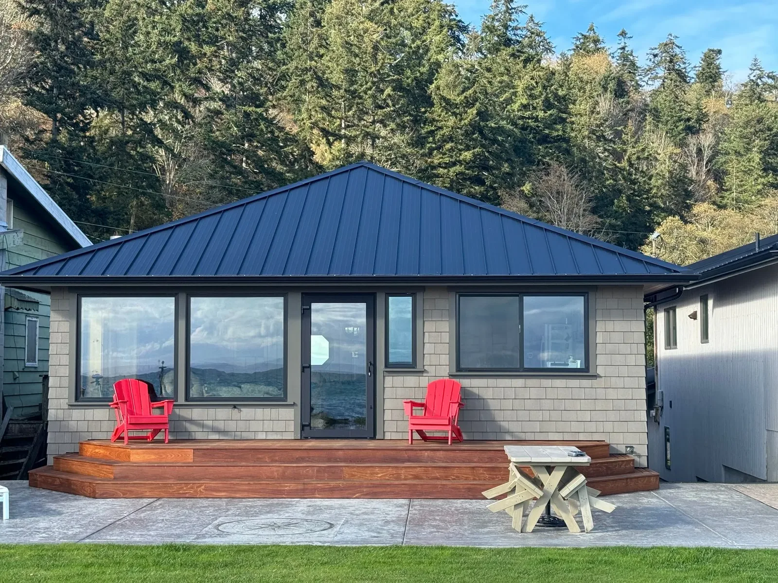 Remodeled island home with cedar shingle siding, a black metal roof and an ironwood deck