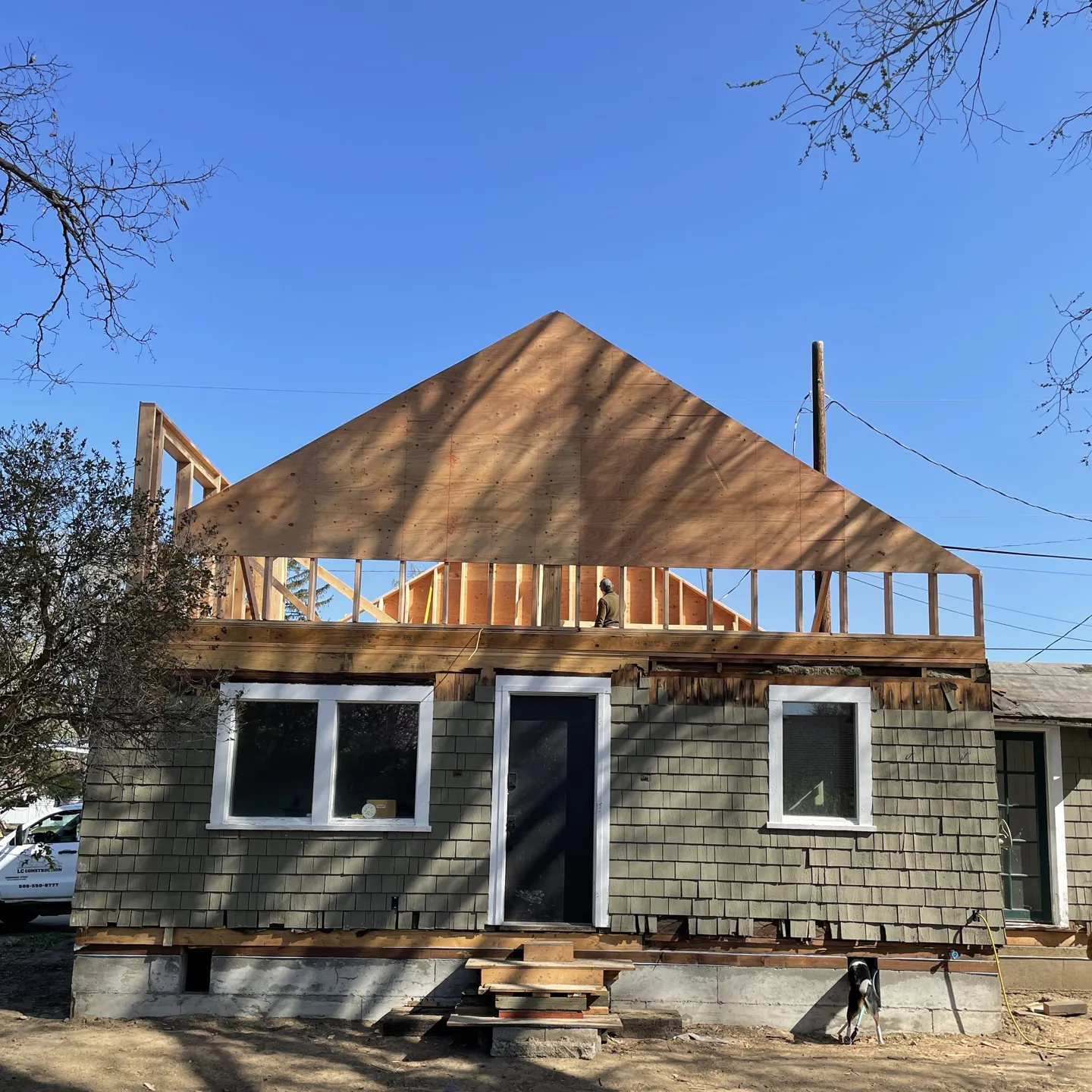 Roof framing going up on a second-story home addition over a shingled house