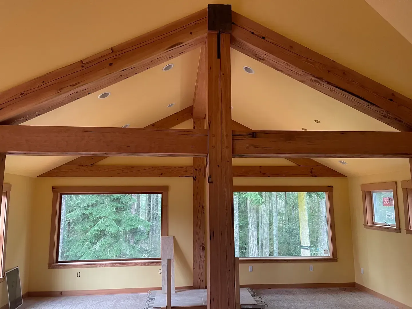 Vaulted great room framed with exposed timber trusses and tall windows